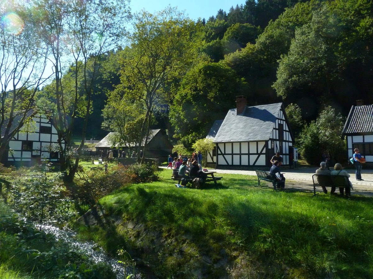 Tal mit Teich und Bäumen, Blick auf drei Fachwerkhäuser.